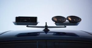 A scale with a speaker set on one side, and an amplifier on the other side, it is on top of a car and balanced in the middle